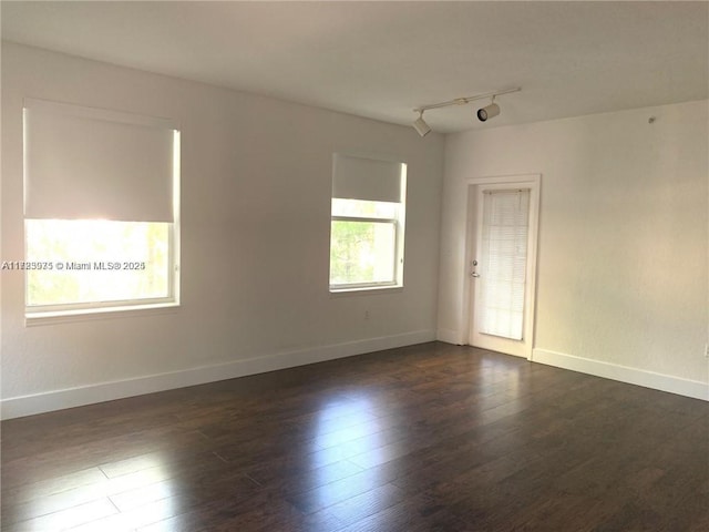 unfurnished room featuring rail lighting and dark wood-type flooring