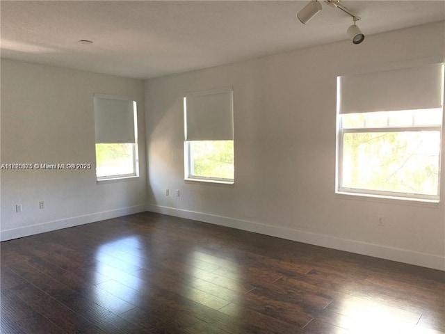 spare room featuring rail lighting and dark wood-type flooring