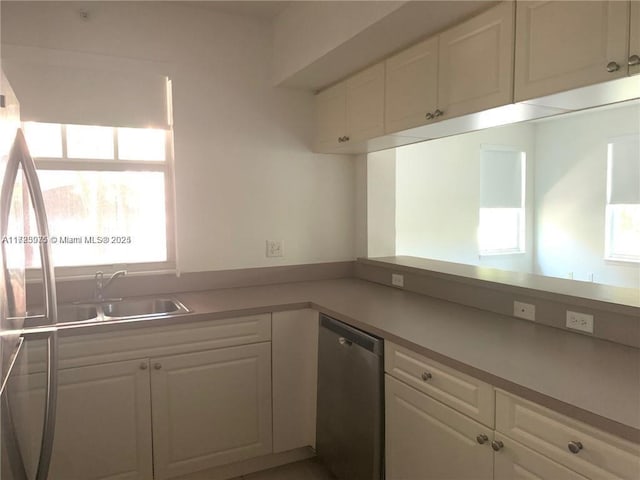 kitchen with stainless steel dishwasher, white cabinets, and sink