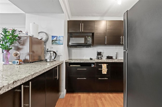 kitchen with black appliances, crown molding, light stone countertops, dark brown cabinets, and light hardwood / wood-style floors