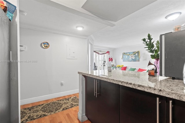 kitchen with light hardwood / wood-style floors, light stone countertops, and crown molding