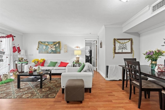 living room featuring plenty of natural light, ornamental molding, and light wood-type flooring