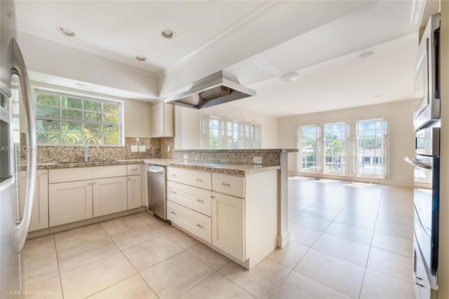 kitchen with sink, kitchen peninsula, extractor fan, decorative backsplash, and appliances with stainless steel finishes