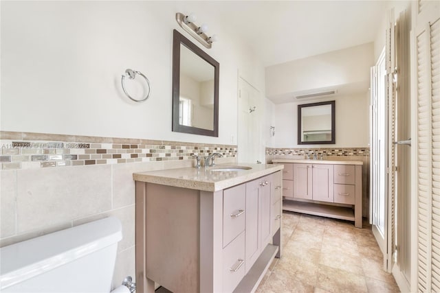 bathroom with vanity, toilet, and tile walls