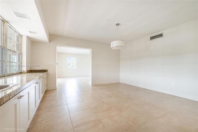 kitchen featuring white cabinetry, sink, light tile patterned floors, and hanging light fixtures