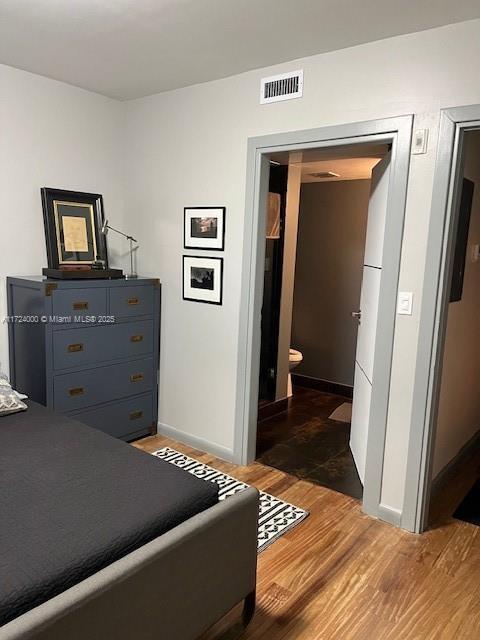 bedroom with dark hardwood / wood-style flooring and connected bathroom