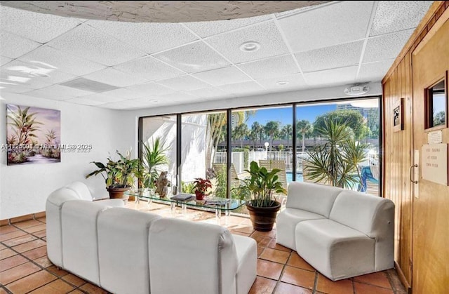 tiled living room with a paneled ceiling