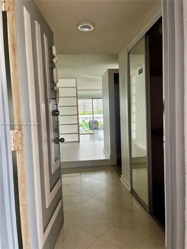 hall with light tile patterned floors and a textured ceiling