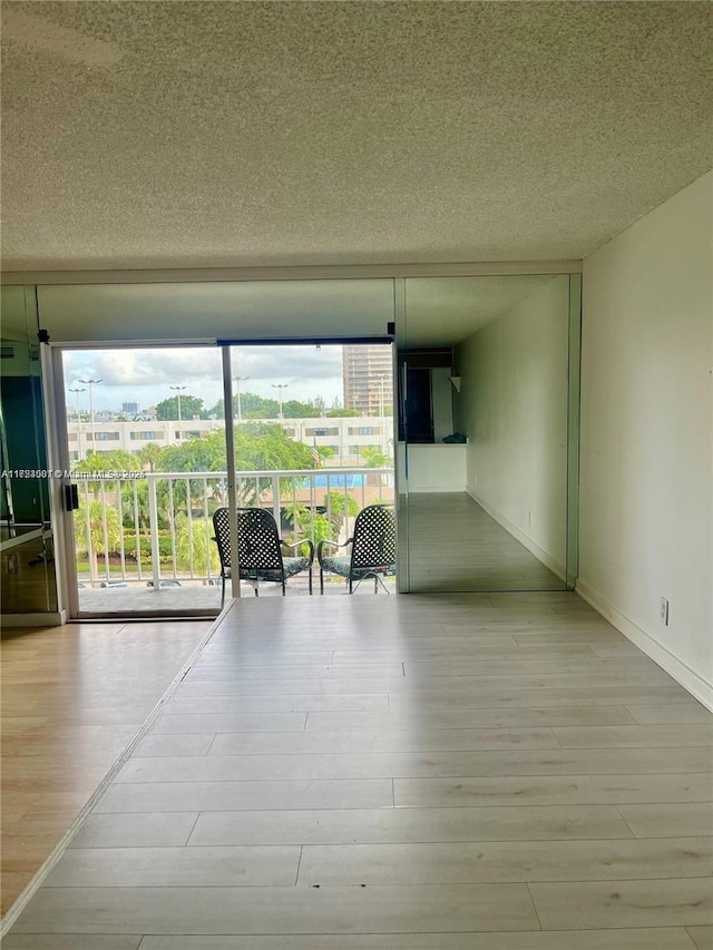 unfurnished room featuring plenty of natural light, light wood-type flooring, and a textured ceiling