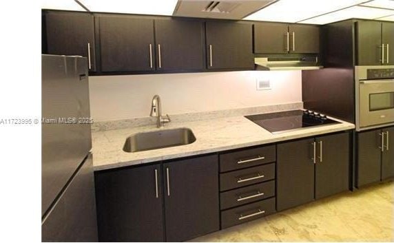 kitchen with wall oven, light stone counters, black electric cooktop, sink, and stainless steel refrigerator