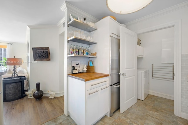 kitchen with washer / dryer, butcher block countertops, tasteful backsplash, and ornamental molding