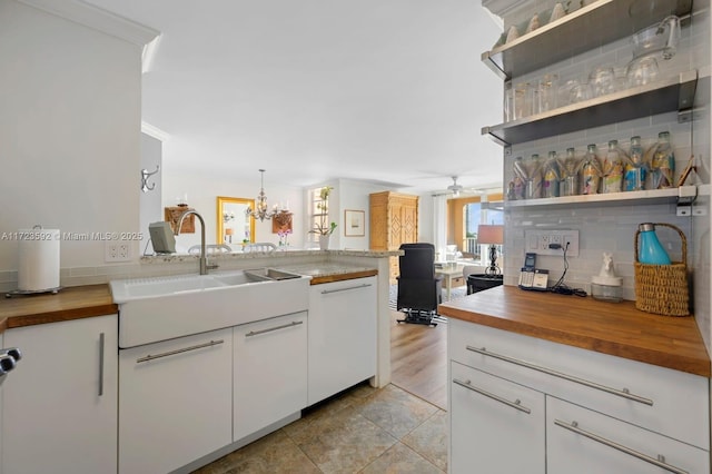 kitchen with wooden counters, pendant lighting, white cabinetry, and dishwasher