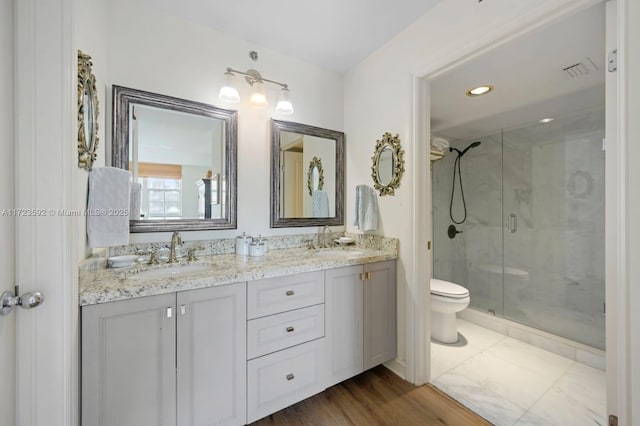 bathroom with hardwood / wood-style floors, vanity, a shower with shower door, and toilet