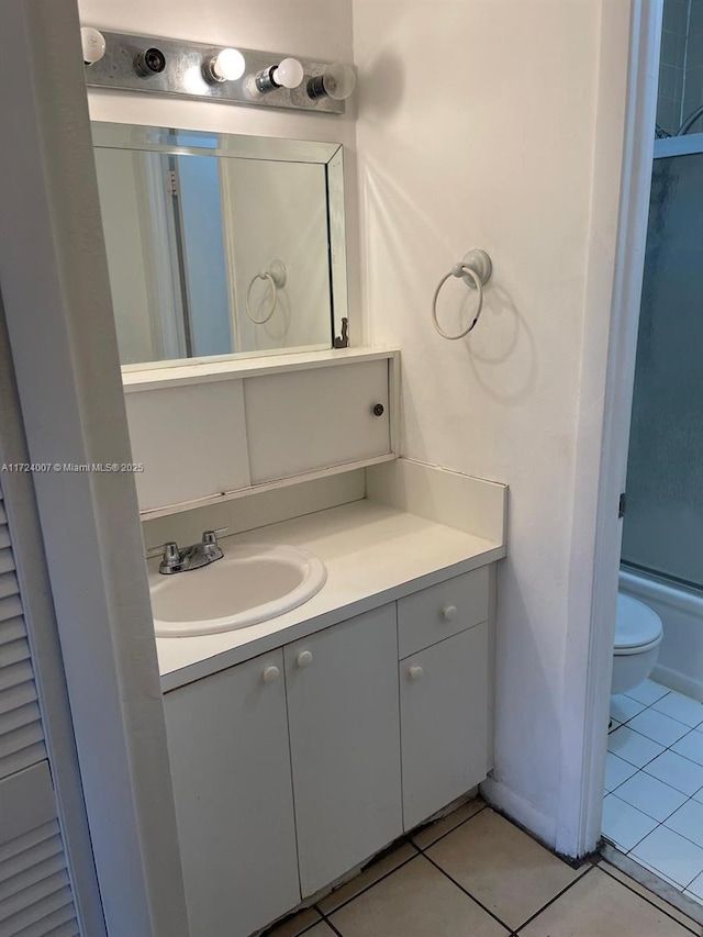 full bathroom featuring tile patterned flooring, vanity, toilet, and bath / shower combo with glass door