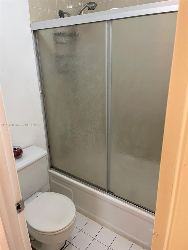 bathroom featuring tile patterned flooring, toilet, and enclosed tub / shower combo