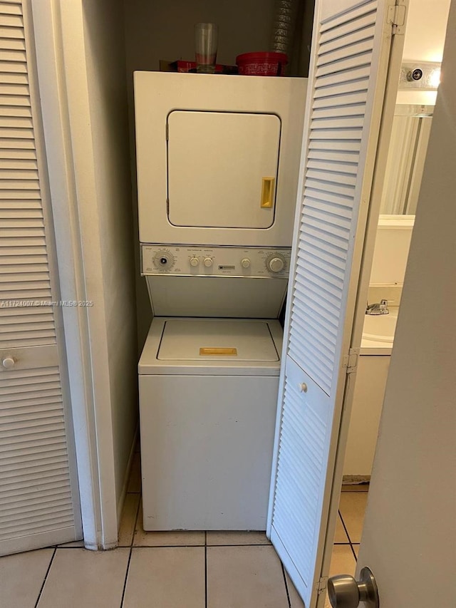 laundry area with stacked washer and dryer and light tile patterned floors