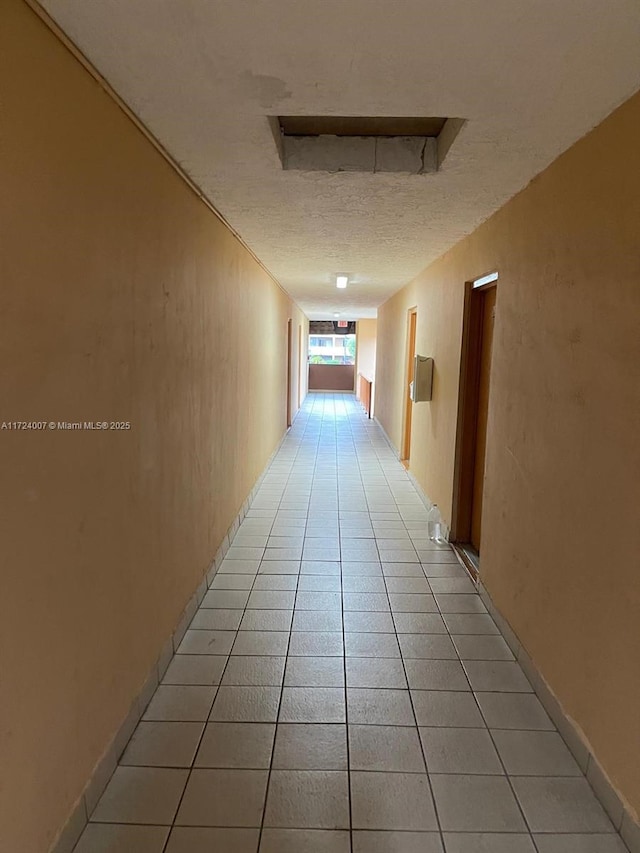 corridor featuring a textured ceiling and light tile patterned flooring