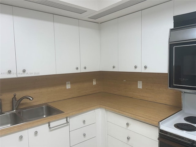 kitchen featuring white electric range, white cabinets, a sink, and light countertops