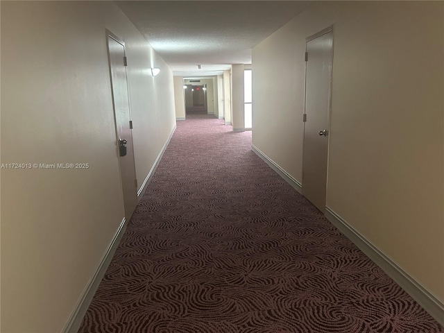 corridor with dark carpet and baseboards