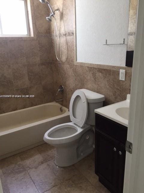 full bathroom featuring tile walls, vanity, tiled shower / bath combo, and toilet