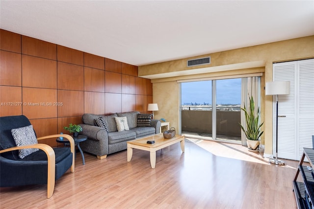 living room featuring light wood-type flooring and wooden walls