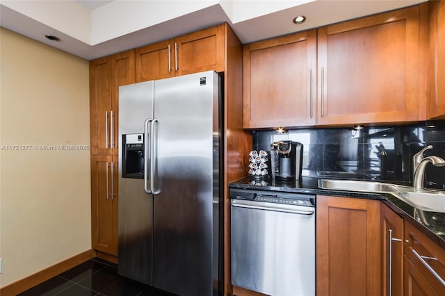 kitchen with tasteful backsplash, sink, dark tile patterned floors, and stainless steel appliances