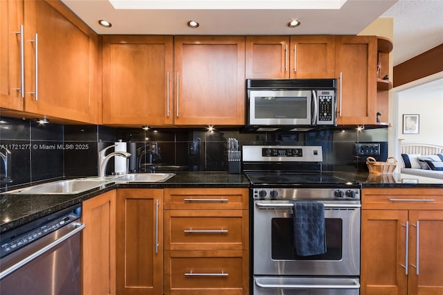 kitchen with decorative backsplash, appliances with stainless steel finishes, dark stone counters, and sink