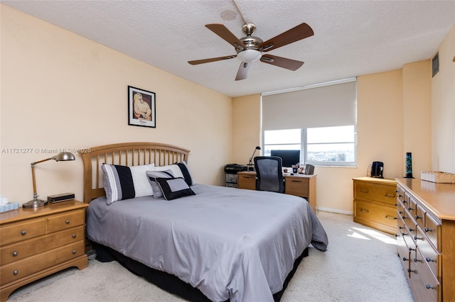 bedroom with ceiling fan, a textured ceiling, and light carpet