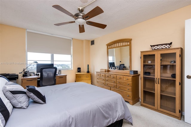 bedroom with a textured ceiling, light colored carpet, and ceiling fan