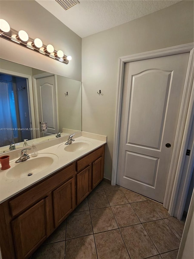 bathroom with tile patterned flooring, a textured ceiling, and vanity