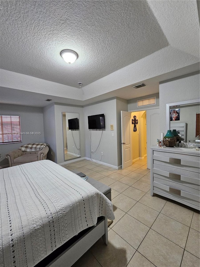 tiled bedroom with a textured ceiling and a raised ceiling