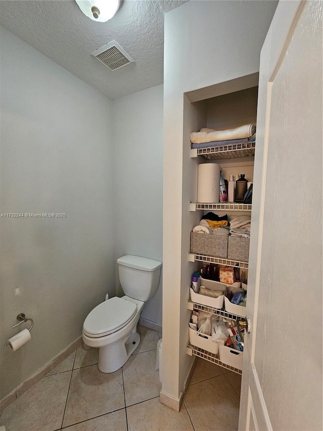 bathroom with toilet, a textured ceiling, and tile patterned floors