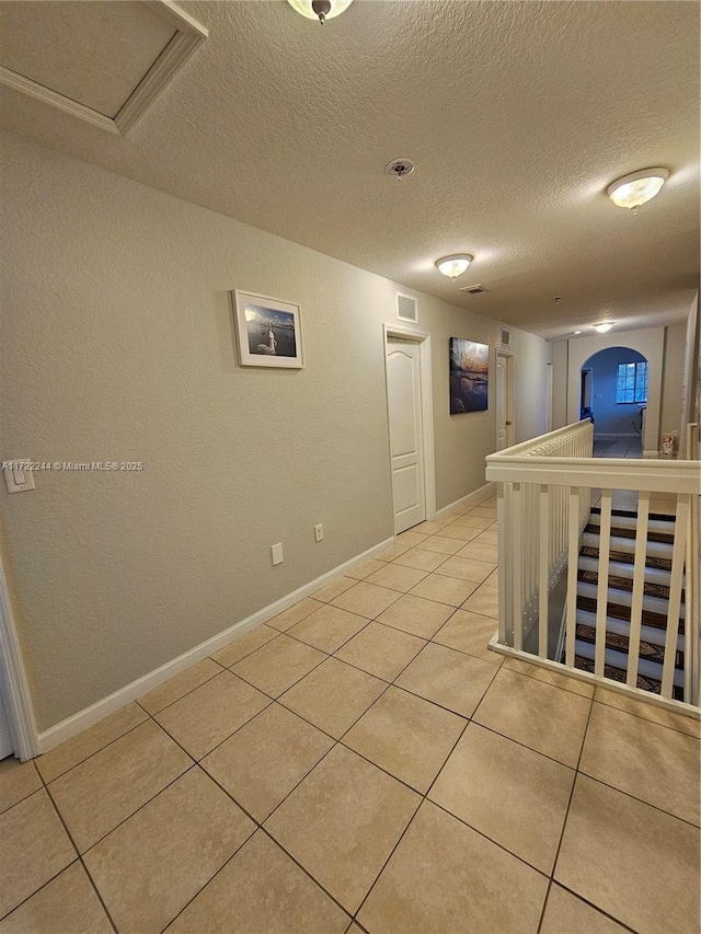 corridor with light tile patterned floors and a textured ceiling