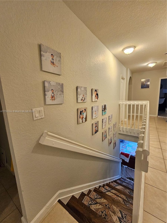 staircase featuring tile patterned flooring and a textured ceiling