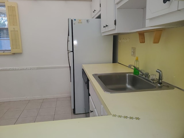 kitchen featuring white cabinets, stainless steel dishwasher, light tile patterned floors, and sink