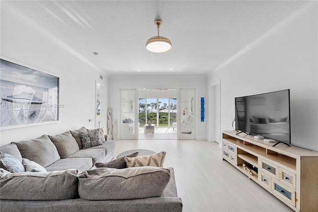 living room featuring light wood-type flooring, a textured ceiling, ceiling fan, and crown molding