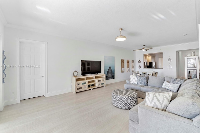 living room featuring ceiling fan, light wood-type flooring, and ornamental molding