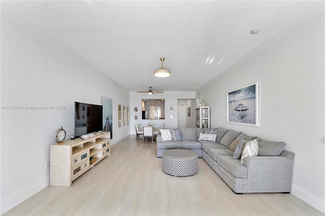 living room featuring ceiling fan, light wood-type flooring, and a textured ceiling