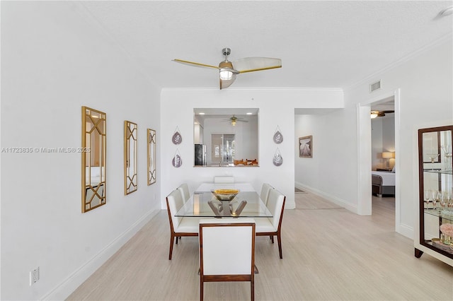 dining room featuring a textured ceiling, light hardwood / wood-style floors, and ornamental molding