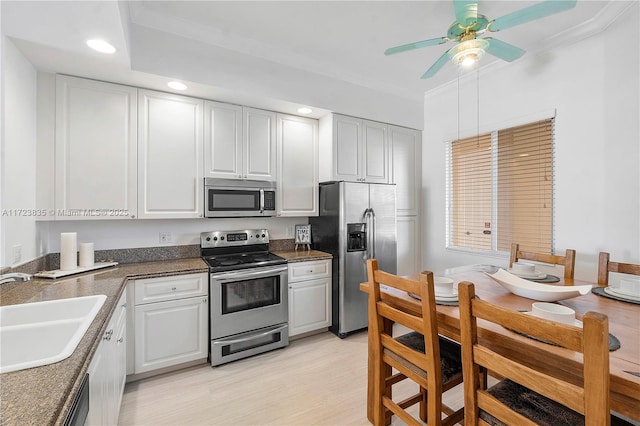 kitchen with appliances with stainless steel finishes, ceiling fan, crown molding, sink, and white cabinets