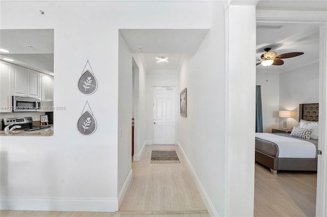 corridor with crown molding and light wood-type flooring