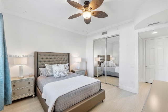 bedroom with ceiling fan, light wood-type flooring, ornamental molding, and a closet