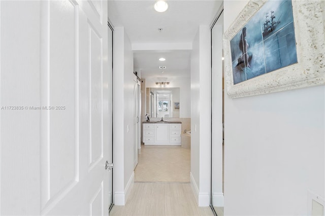 hallway with a barn door and light hardwood / wood-style floors