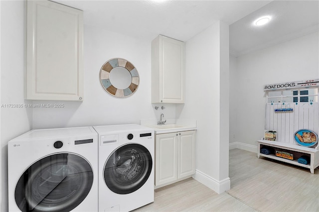 laundry room with sink, light hardwood / wood-style flooring, cabinets, and independent washer and dryer