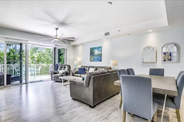 living room with a textured ceiling, light hardwood / wood-style floors, and ceiling fan