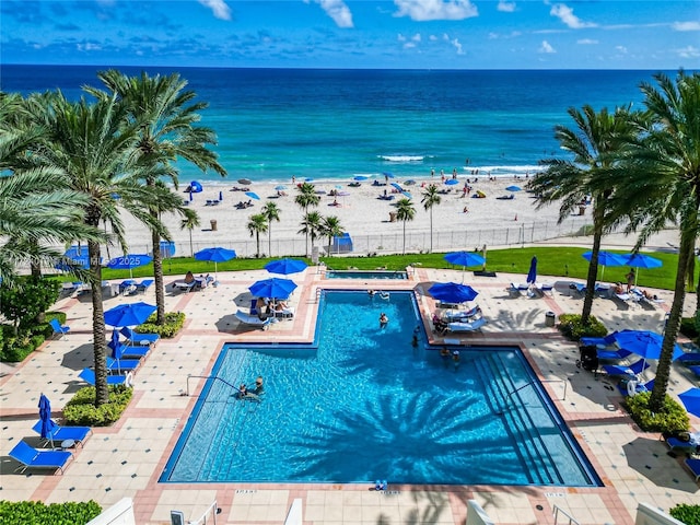 view of pool with a water view, a patio, and a beach view