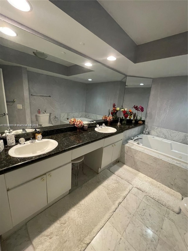 bathroom with vanity, tiled bath, and toilet