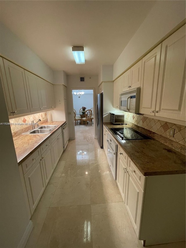 kitchen featuring decorative backsplash, stainless steel appliances, white cabinetry, and sink