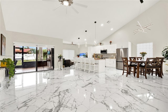 kitchen with white cabinetry, tasteful backsplash, decorative light fixtures, a kitchen bar, and appliances with stainless steel finishes