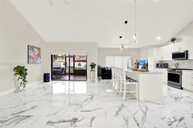 kitchen featuring a breakfast bar, stainless steel appliances, a kitchen island with sink, pendant lighting, and white cabinetry